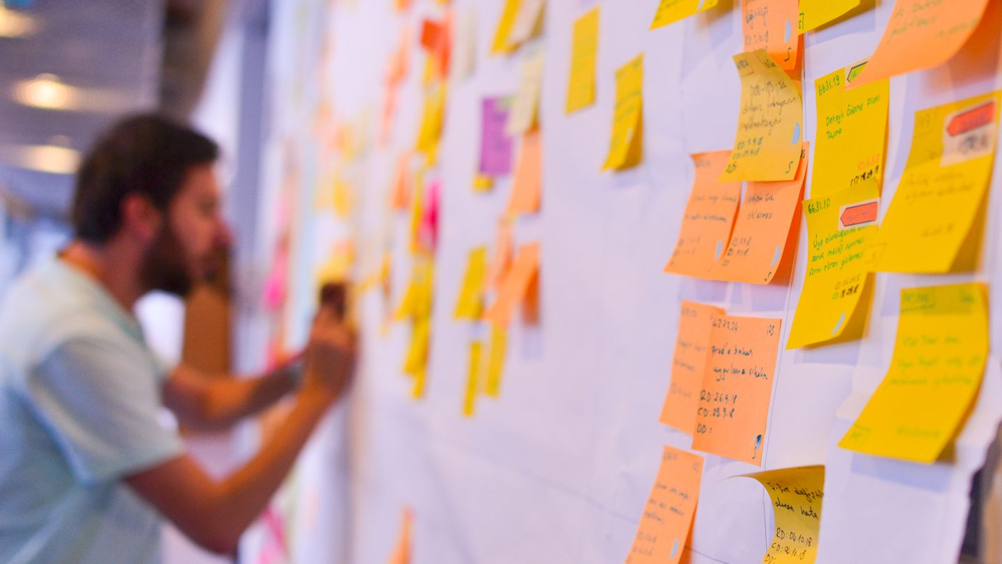 programiści przy stole z laptopami i karteczkami planujący sprint